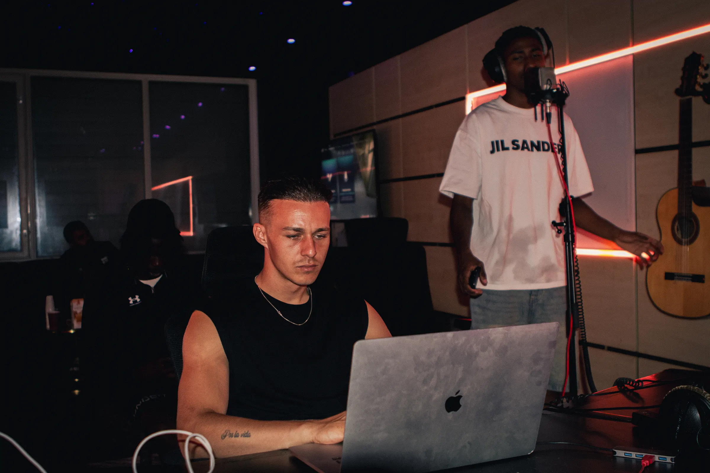 Producer achter de laptop terwijl een vocalist opneemt in Studio 2