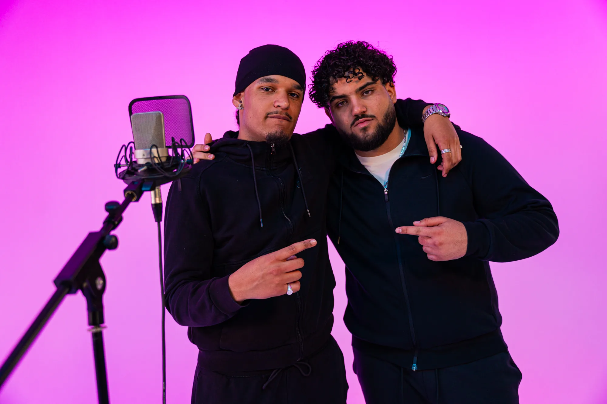 Twee rappers bij de microfoon voor een roze achtergrond